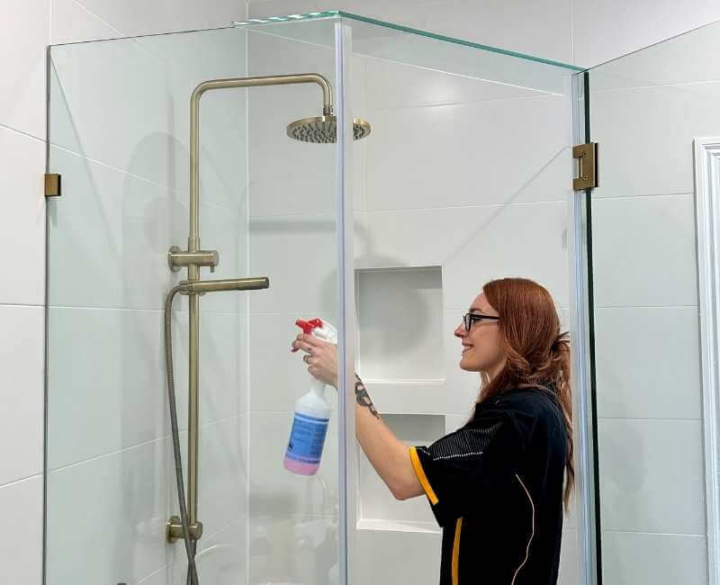 Maid2Match Brisbane Professional Cleaner, Mariachiara using shower cleaning spray solution to clean shower area