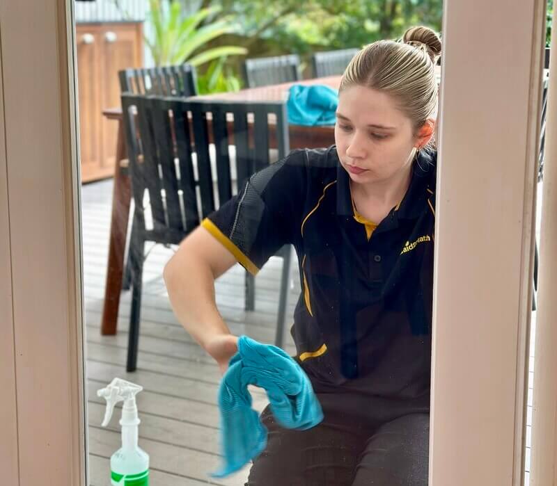 Professional house cleaner Kate-lyn cleaning a glass door