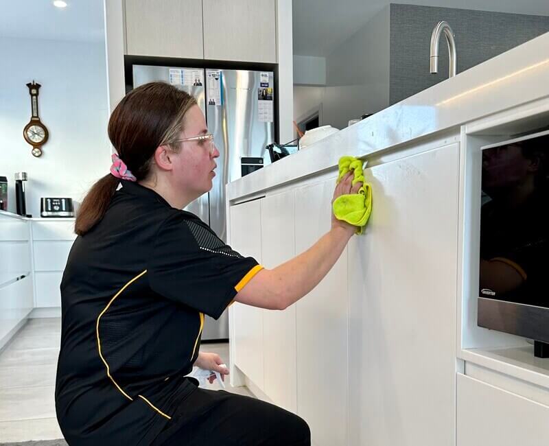 professional cleaner Kirsten wiping the kitchen cabinets