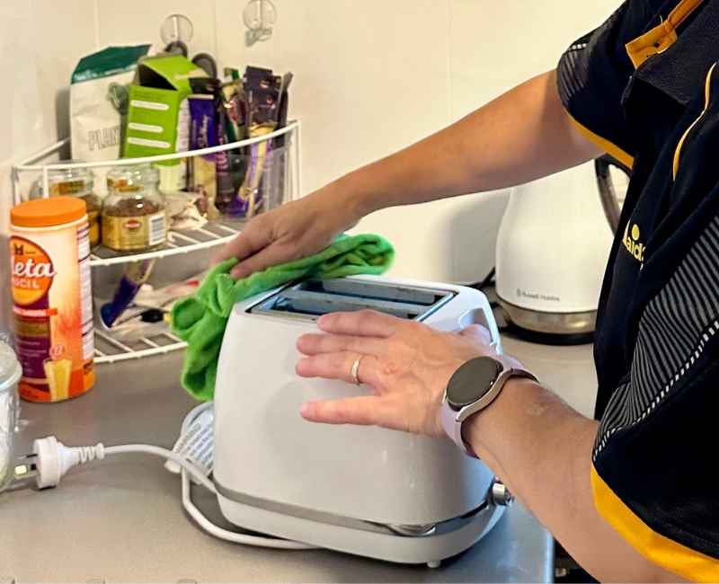 Professional Cleaner Sharlene cleans a toaster in the kitchen