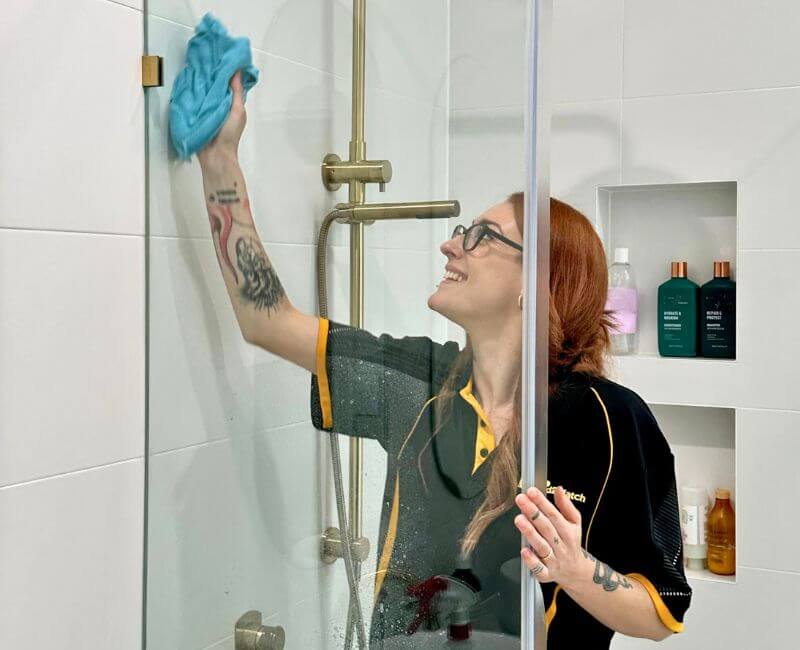 Maid2Match professional house cleaner Mariachiara cleaning the shower glass