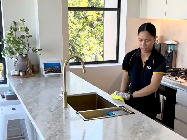 Maid2Match Brisbane professional house cleaner Paige wiping down marble benchtop with mircofibre cloth