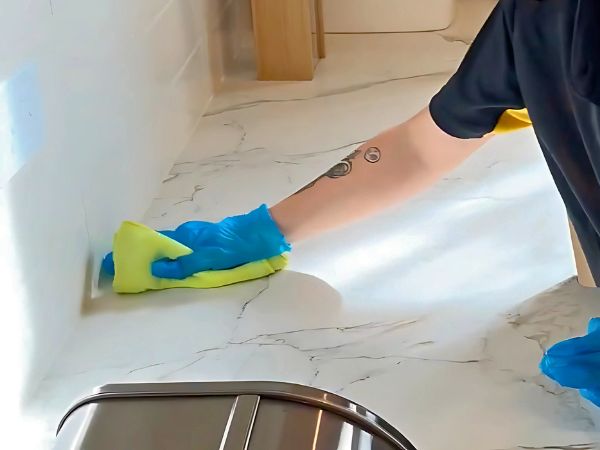 hand cleaning marble benchtop up close