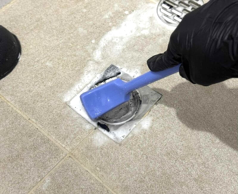 cleaning shower drain with brush and soap