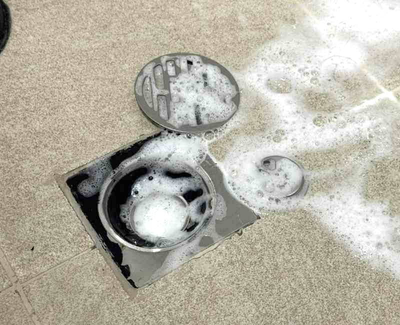 Shower drain components soaked in soap for cleaning