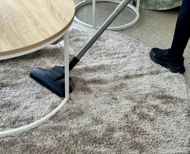 cleaner using a vacuum to clean a shag rug