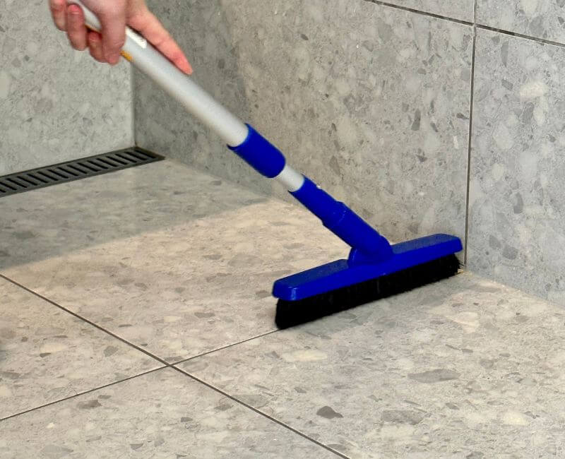 house-cleaner-cleaning-floor-tiles bathroom floor tiles being cleaned with brush