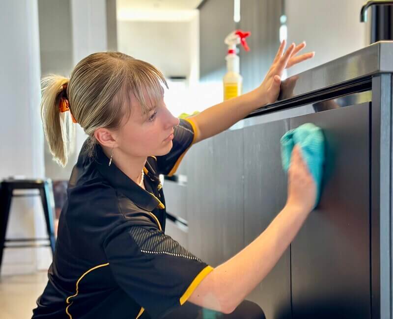 Maid2Match-house-cleaner-wiping-cabinets Maid2Match Brisbane professional cleaner wiping dark colored cabinets with cloth