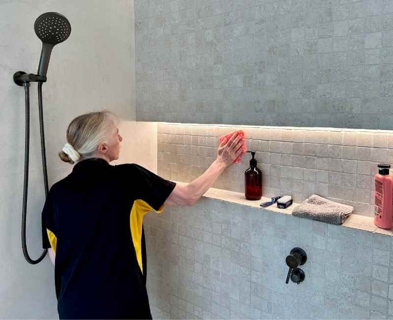 Maid2Match Gold Coast house cleaner cleaning natural stone shower tiles with microfibre cloth