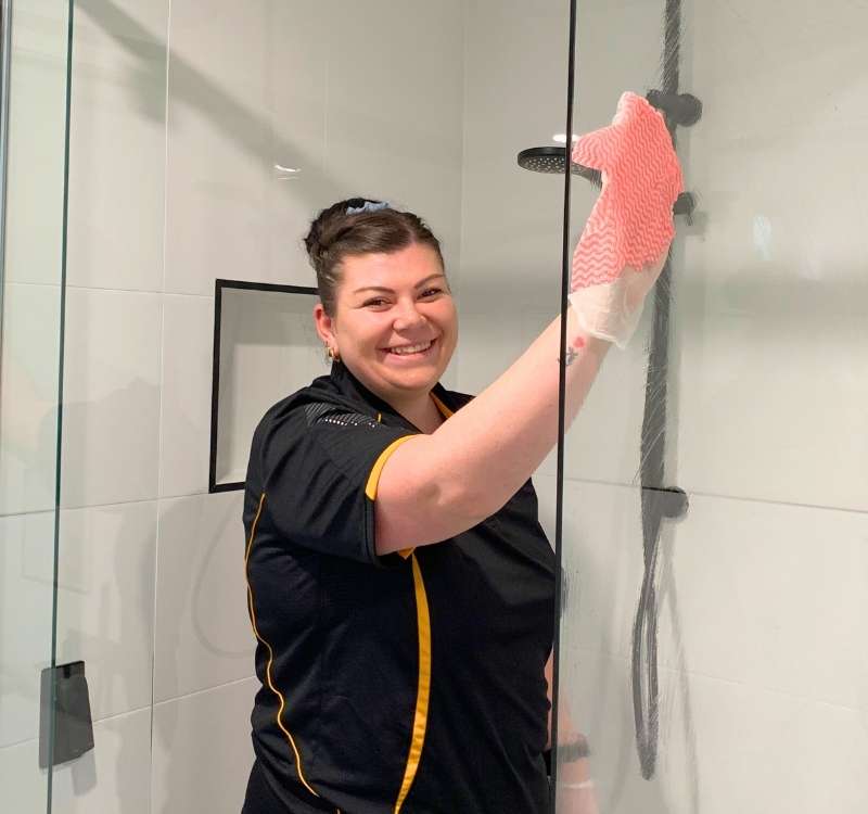 Maid2Match-professional-house-cleaner-cleaning-shower-glass Maid2Match Brisbane professional house cleaner smiling while cleaning shower glass