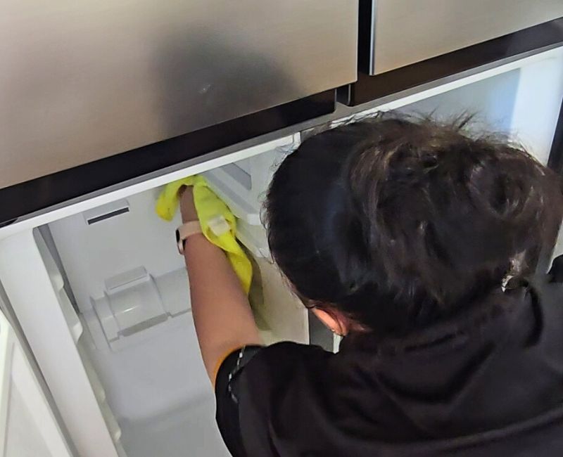 Maid2Match-Geelong-cleaner-cleaning-the-inside-of-the-freezer Maid2Match Geelong House Cleaning - professional house cleaner reaching to clean inside a freezer with microfibre cloth