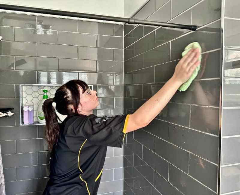 Maid2Match house cleaner Tullie wiping shower tiles with microfibre cloth to dry