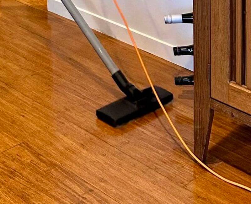 Cleaner using vacuum to remove dirt from bamboo flooring