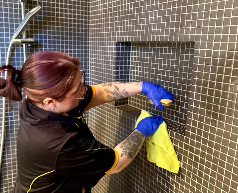 Maid2Match Geelong professional house cleaner cleaning off soap scum from shower tiles
