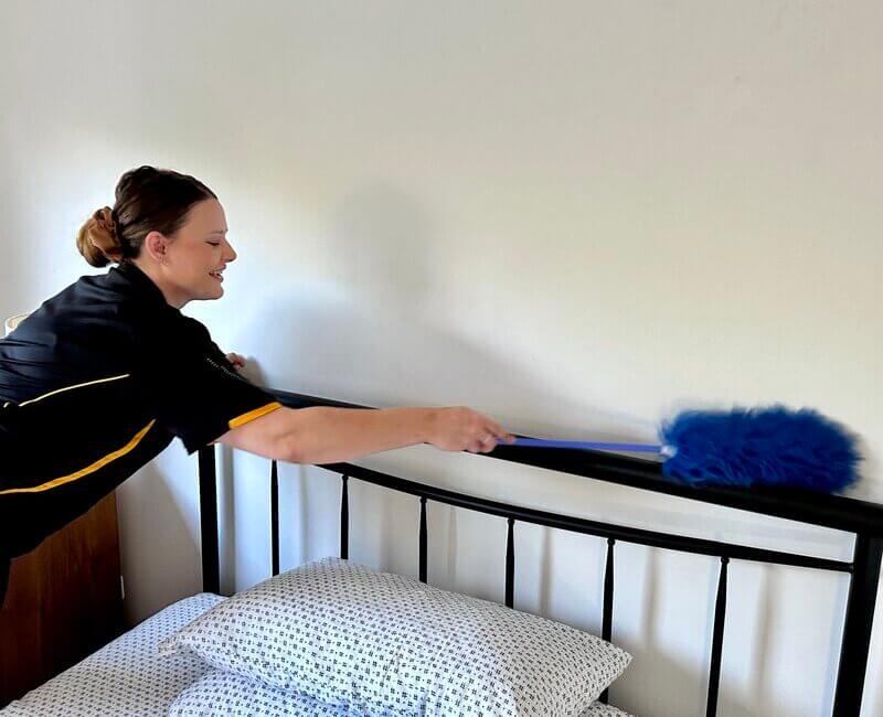 Professional-NDIS-cleaner-dusting-bedframe Brisbane NDIS professional cleaner dusting the bedframe