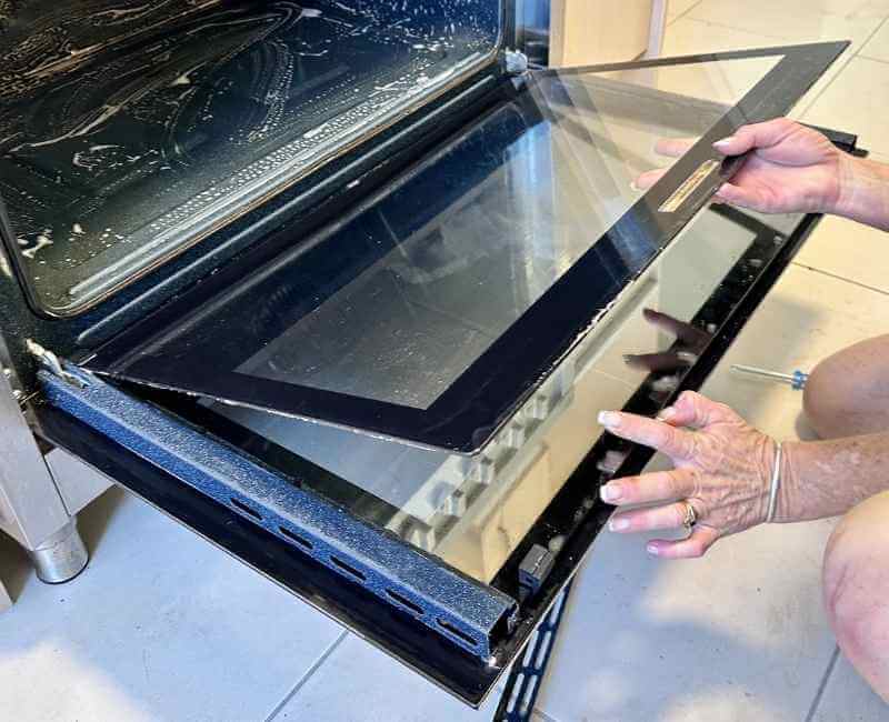 Maid2Match professional house cleaner taking apart oven glass door during oven cleaning