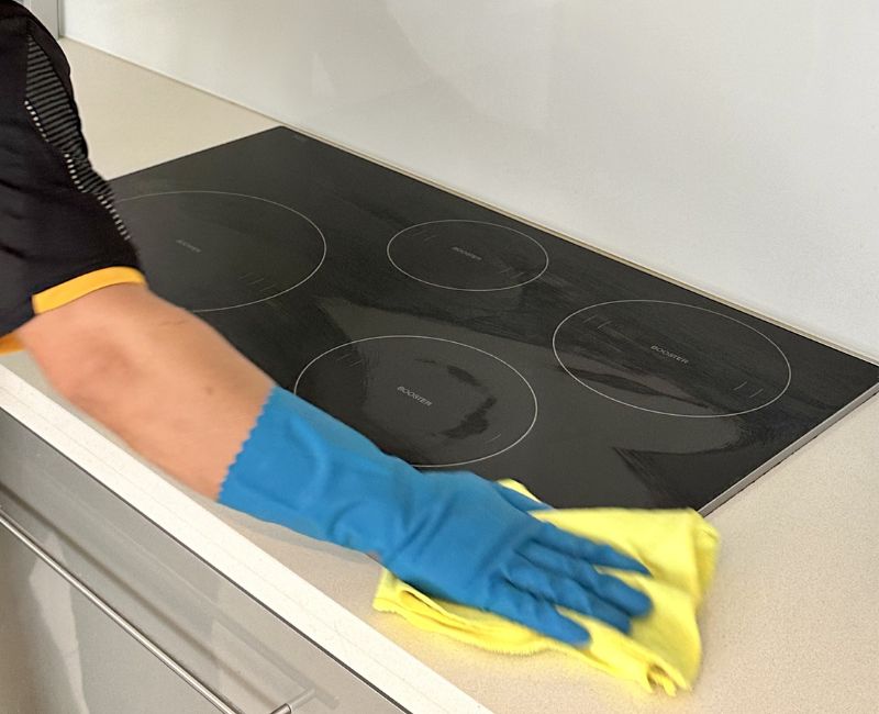 Cleaning expert cleans induction stove top with microfibre cloth
