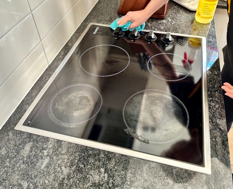 Expert house cleaner cleaning glass stove top