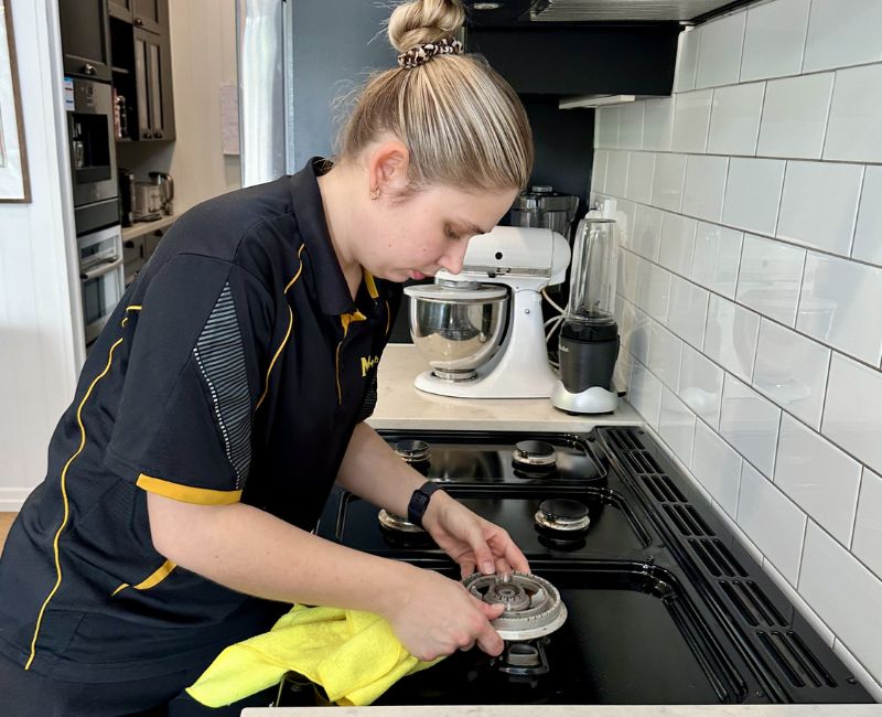 Maid2Match professionally trained house cleaner cleaning gas stove top
