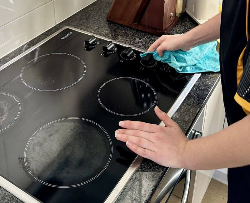 Maid2Match fully trained house cleaner cleaning knobs of glass cooktop with microfibre cloth