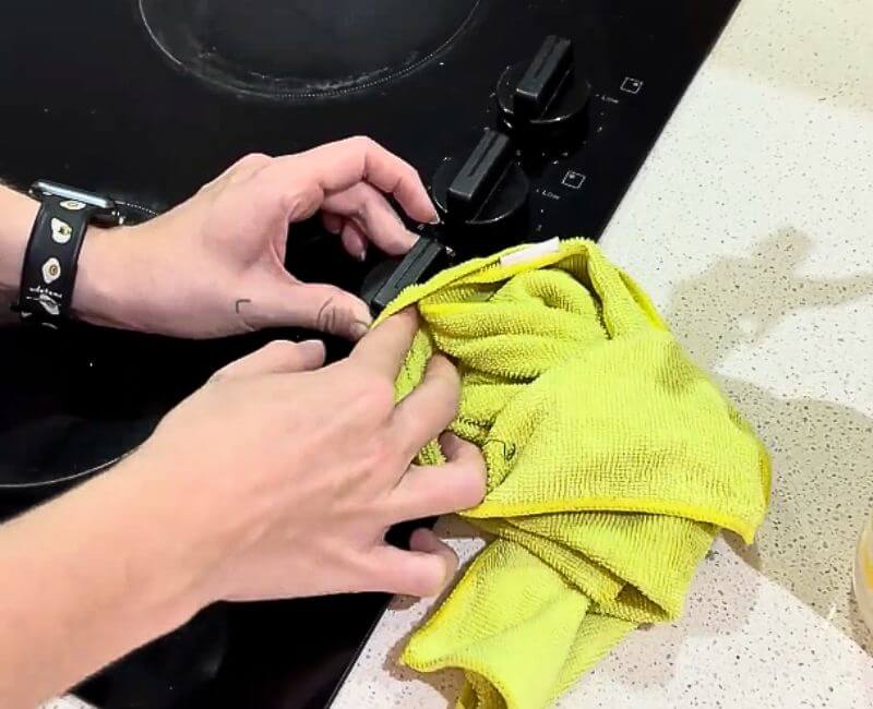 Maid2Match house cleaner wiping electric stove top knobs with microfibre cloth