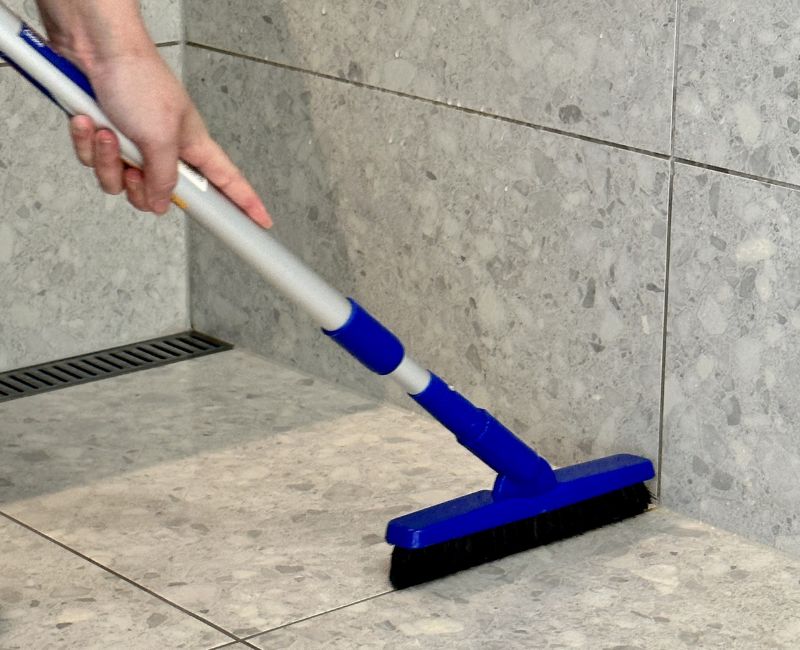 Maid2Match experienced cleaner brushing shower tile grout