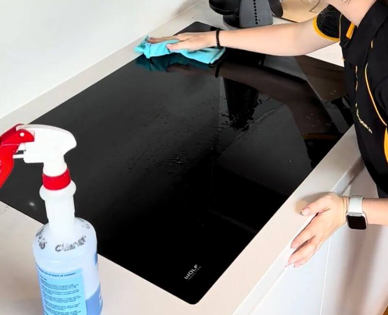 Maid2Match expert cleaner wiping cleaner off a glass cooktop