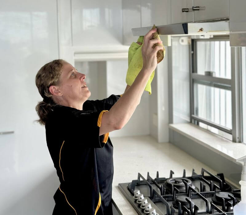 Maid2Match Brisbane fully trained house cleaner cleaning rangehood in the kitchen during a house clean