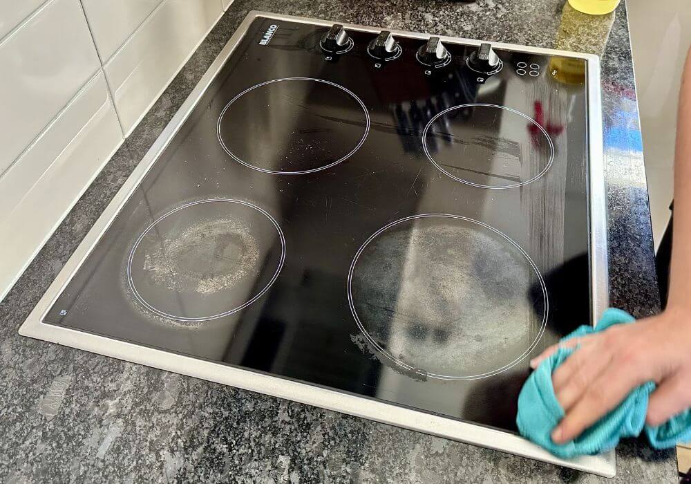 Maid2Match professionally trained cleaner using microfibre cloth to clean glass stove top