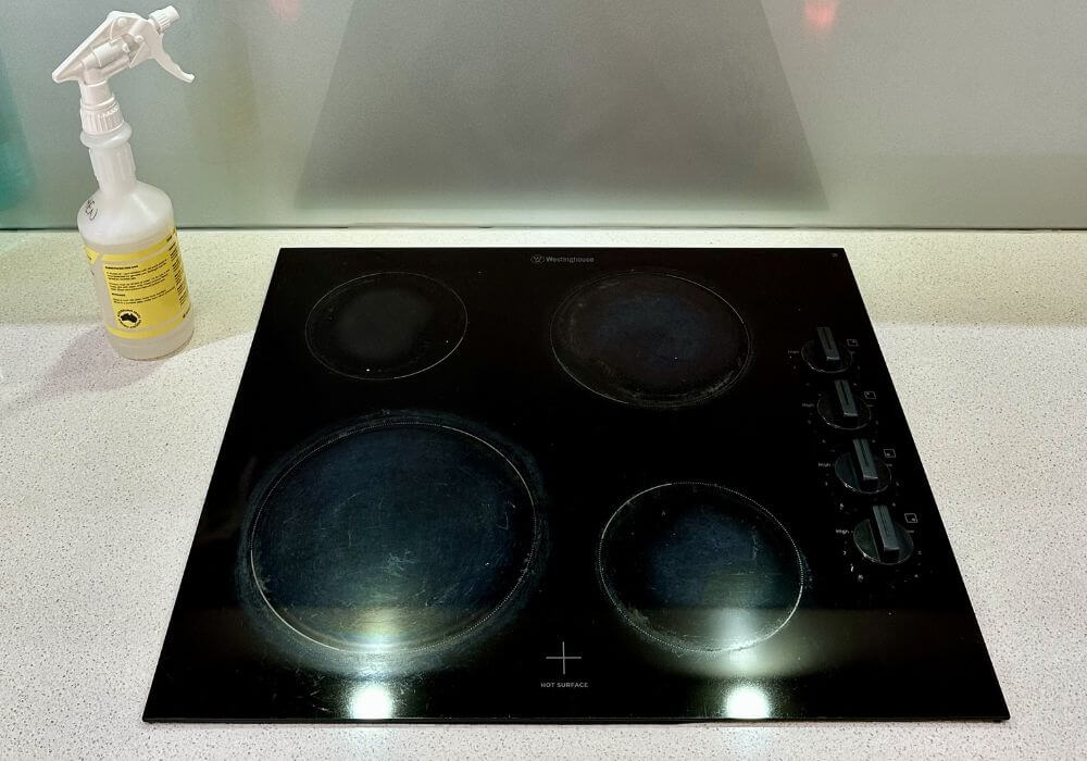 clean-electric-stove-top-feature A newly cleaned electric stovetop and a spray cleaner on the top left corner