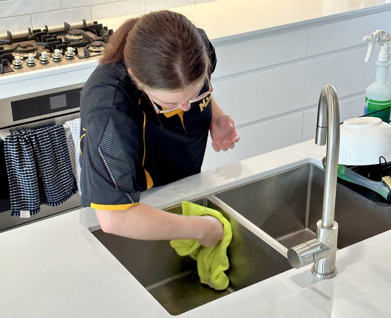 Maid2Match house cleaning professional cleaner Kirsten cleaning stainless steel kitchen sink with microfibre cloth