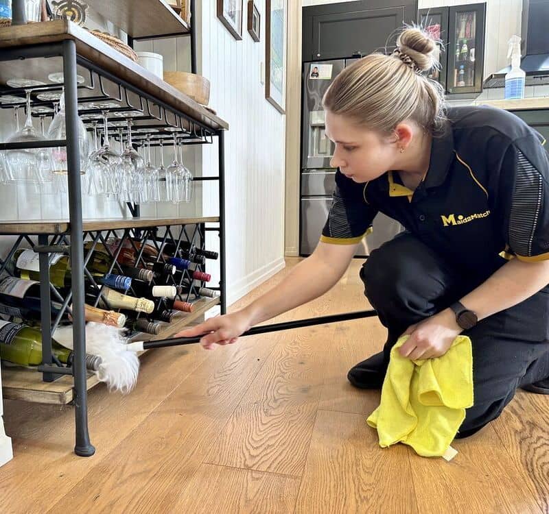 house cleaner Kate-lyn dusting wine bottles in the kitchen