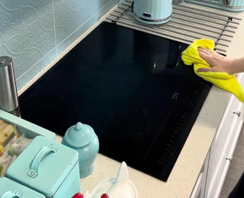 Maid2Match professional house cleaner cleaning an induction stove top with microfibre cloth