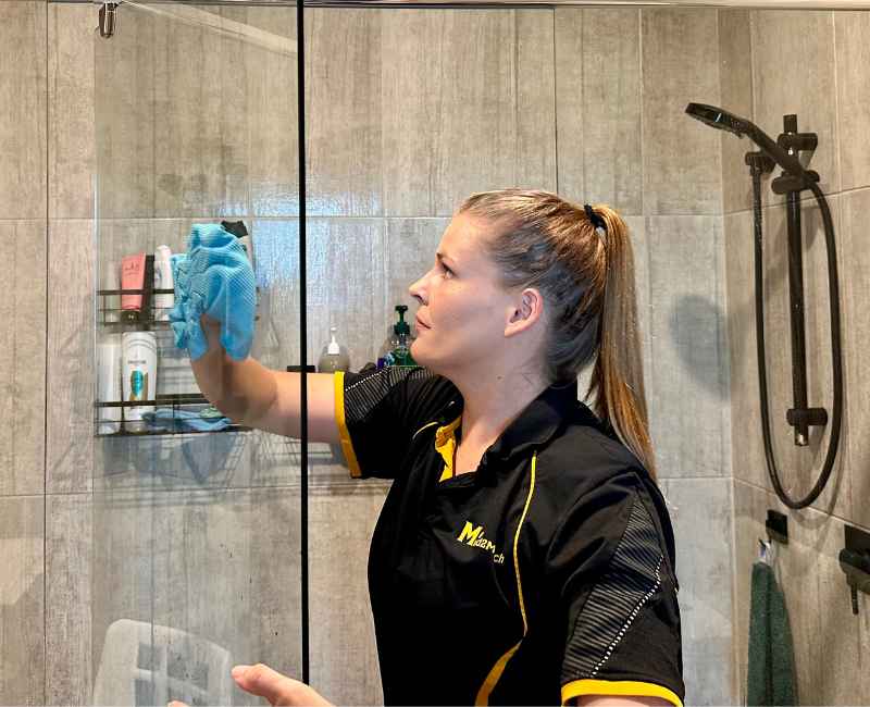 Courtney changing careers as a house cleaner cleaning bathroom shower glass