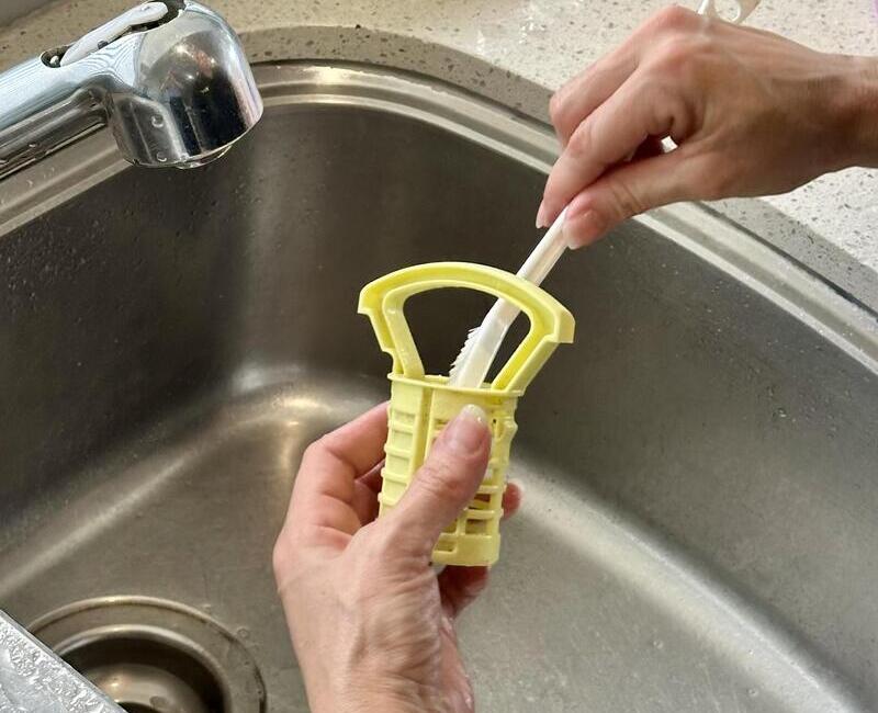House cleaner cleaning dishwasher filter with a brush