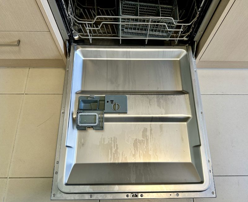 Chalky white limescale buildup inside the dishwasher