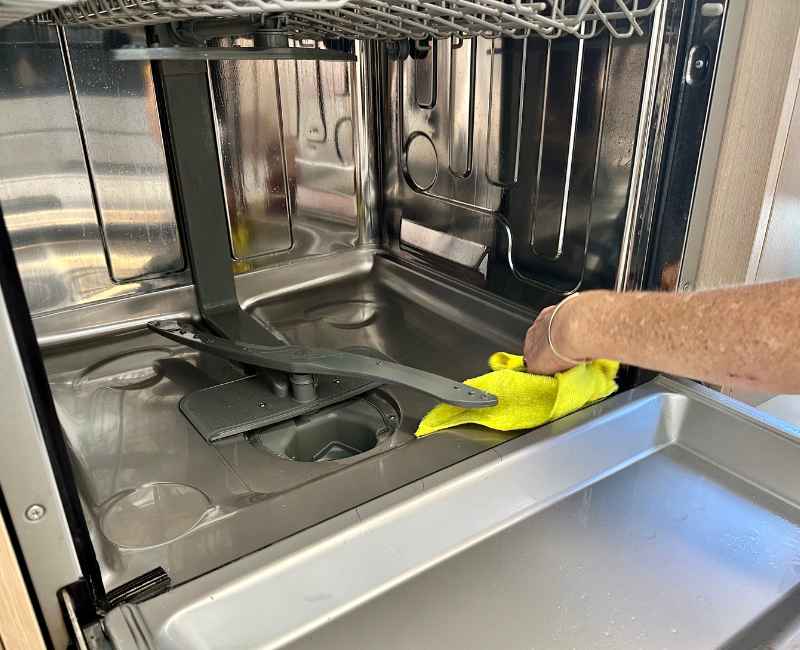 House cleaner removing food debris from dishwasher