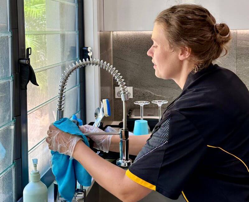 Maid2Match Gold Coast house cleaner Acama cleaning a kitchen sink faucet with microfibre cloth