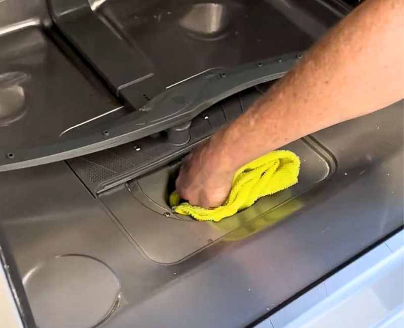 Cleaning a dishwasher drain with microfibre cloth.