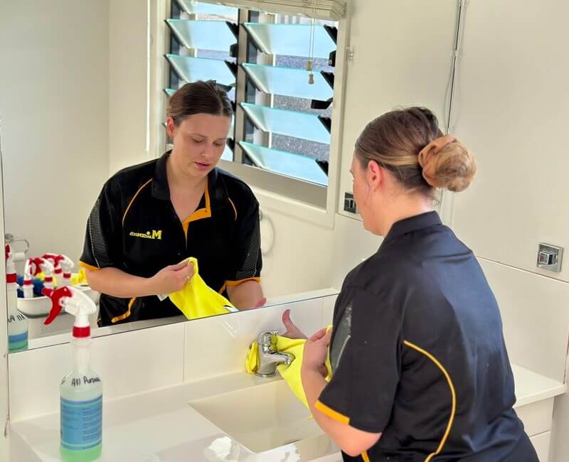 Brisbane cleaner Alison cleaning the faucet of the bathroom sink