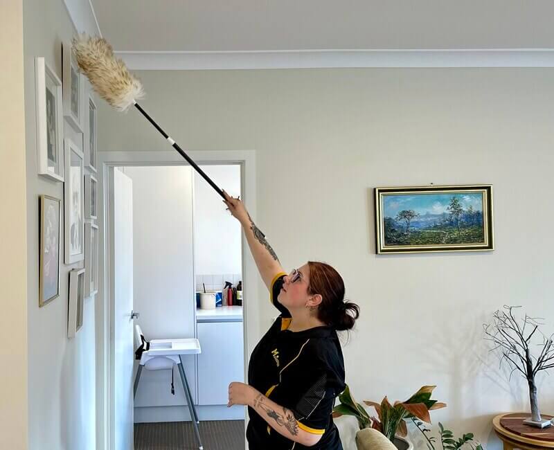 Maid2Match Geelong experienced house cleaner Paris dusting items in the living room