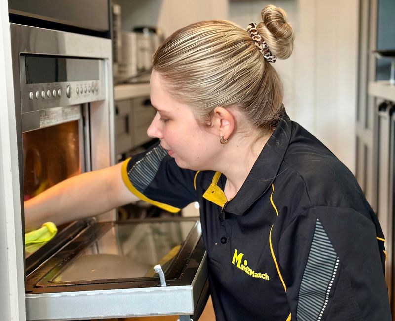 Maid2Match Brisbane house cleaner Kate-Lyn cleaning the inside of a microwave