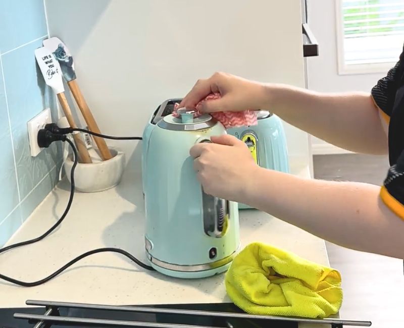 Maid2Match experienced cleaner wiping limescale off kettle exterior