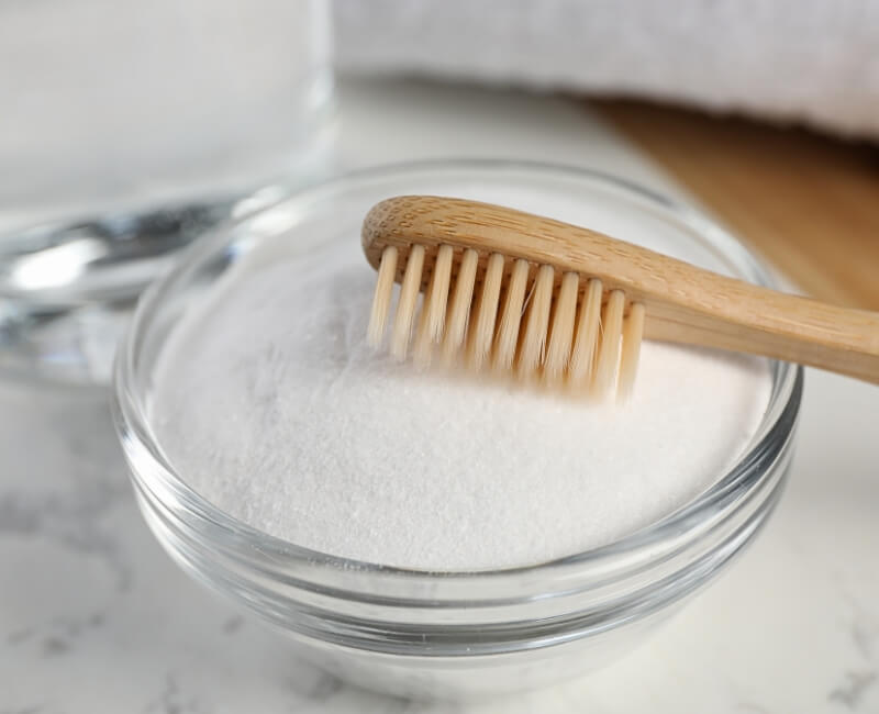 borax powder and toothbrush in a clear bowl