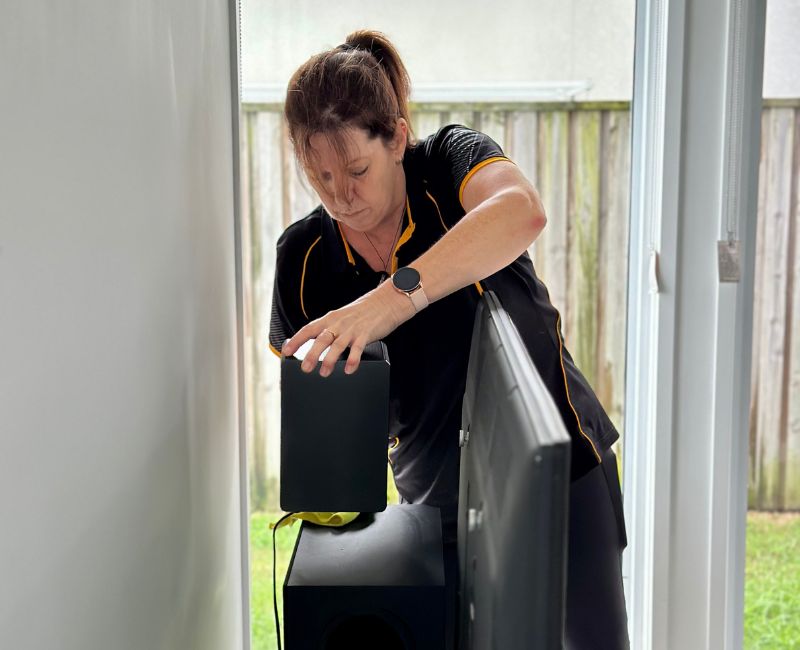 Maid2Match domestic cleaner wiping the dust build up behind the television