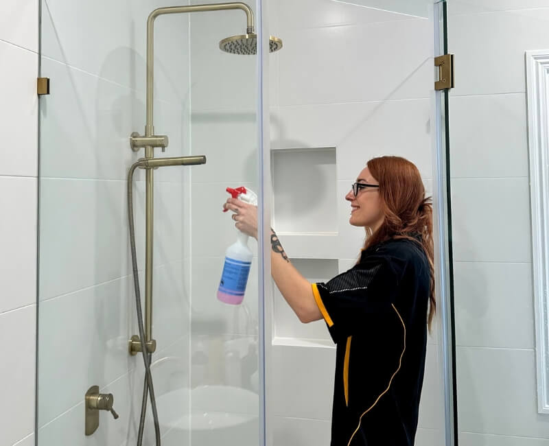 professional house cleaner cleaning the shower area