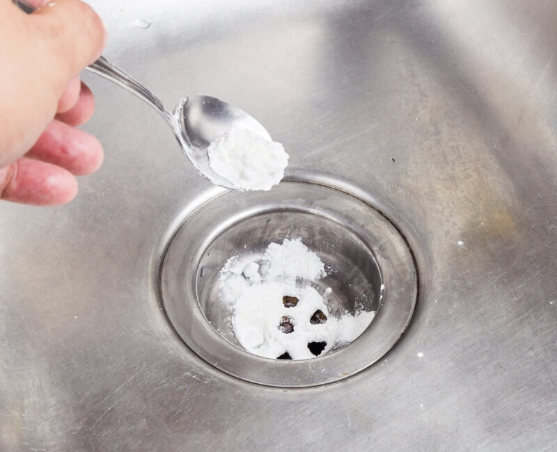 Pouring borax powder slowly into sink drain