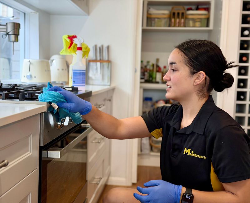 Maid2Match professional cleaner Timea wiping a stove top