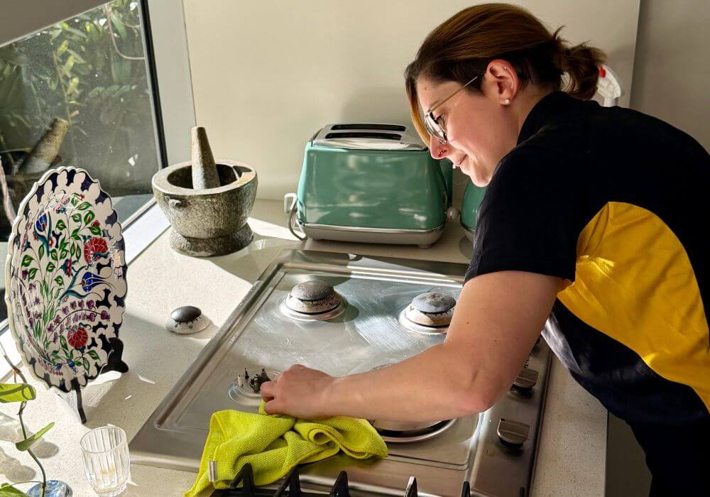professional-house-cleaning-time-feature Maid2Match domestic cleaner in Brisbane cleaning a stove top thoroughly with microfibre cloth