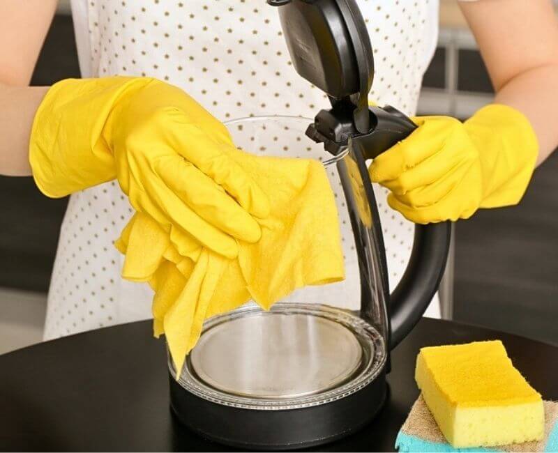 Wiping stains off glass kettle exterior with microfibre cloth